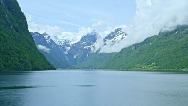 time lapse of tranquil and calm Oldevatnet glacial lake in front of the melting Briksdalsbren glacier in Norway with snow capped mountains.