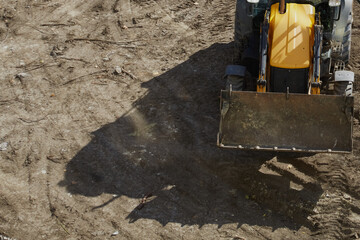 Bucket and front of bulldozer casts shadow on earthen site, bulldozer on construction site