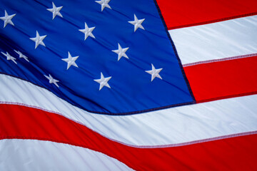 Close up of flag of United States of America while blowing in the wind while lit up by sunshine.
