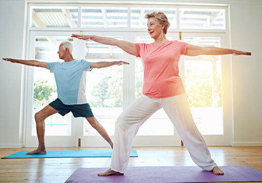 Yoga, stretching and mature couple in home for fitness, health and wellness with warrior pose. Workout, senior man and woman on mat for pilates, balance and body care exercise together in retirement.