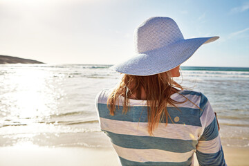 Woman, back and hat at beach for holiday, fun and break as tourist in Miami. Female person, coast...