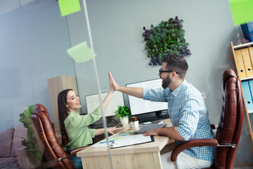 Photo of happy smiling coworkers wear shirts giving arms palms high five indoors workplace...