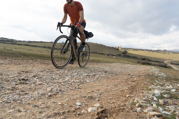 Fototapeta premium A cyclist on a gravel bike engages in bikepacking through a mountainous trail, standing on the pedals while riding. A scene of adventure and endurance in nature.