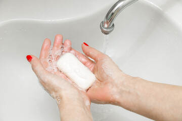 woman washing her hands with soap in the bathroom
