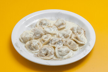 boiled dumplings on a white plate on a yellow background