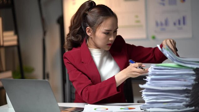 Serious business woman is stressed and bored with too much paperwork to miss the deadline. She is working tiring overtime. Overworked woman is