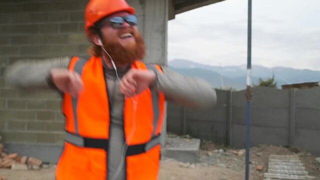 Confident caucasian man dancing happily at construction site, with raised up hands in sunglasses outdoors,  celebrates end of work shift.