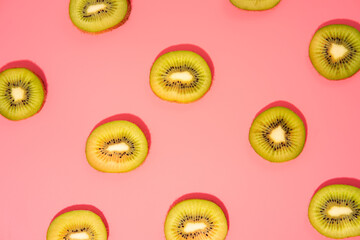 Flat lay of kiwi slices on a pink background