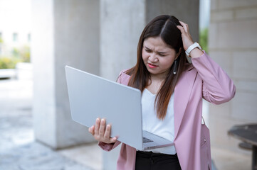 Fototapeta premium A person who looks confused or irritated while holding a laptop This may indicate that the person is having trouble completing an online transaction or a technical issue.