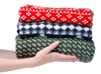 Stack folded knitted sweaters Christmas in hand on white background isolation