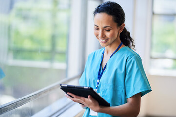 Smiling Nurse in Hospital Scrubs Using Digital Tablet in Modern Medical Facility
