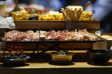 Shallow depth of field (selective focus) details with various meats (charcuterie) at a buffet.