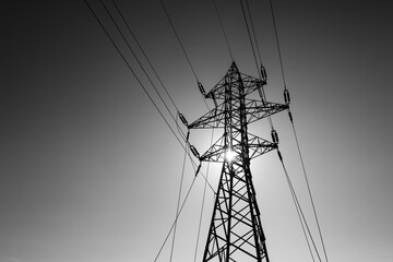 Black and white image with a high voltage electrical pole.