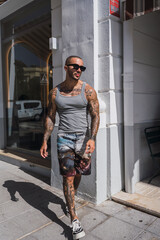 Chico joven musculoso y tatuado con camiseta de tirantas gris en una caferteria