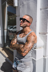 Chico joven musculoso y tatuado con camiseta de tirantas gris en una caferteria