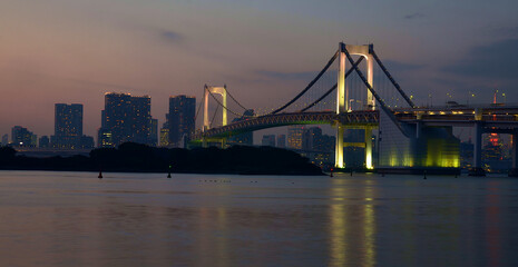 Rainbow bridge and city view at sunset in Odaiba city of Japan.