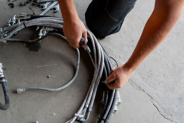 Garage workshop mechanic close up working on hydraulic and electric pipes close up on grey pavement ground close up