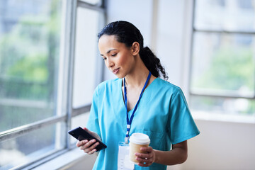 Focused Doctor Checking Phone While Holding Coffee in the Hospital