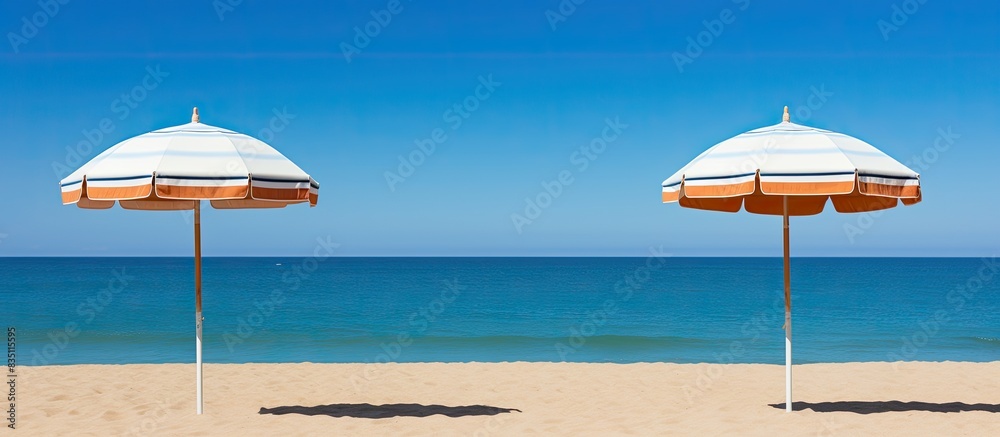 Poster Sun umbrellas on a backdrop of the sea, with a clear blue sky providing a serene setting for a relaxing day at the beach; ideal for a copy space image.