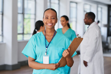 Smiling Medical Professional Holding Clipboard in Multi-Ethnic Hospital Setting