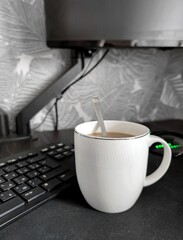 cup of coffee on the computer table with keyboard and mouse with monitor