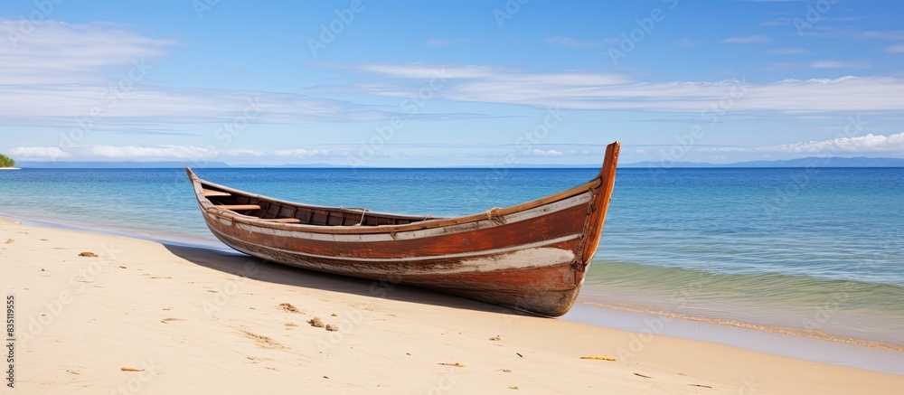 Poster Wooden canoe resting on the sandy beach with a clear view of the ocean in the background, ideal for adding text or design in the copy space image.