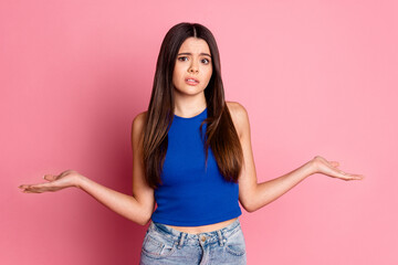 Photo of doubtful unsure girl wear tank top shrugging shoulders isolated pink color background