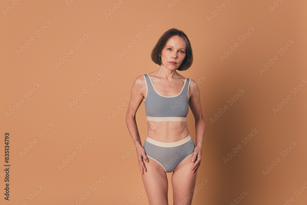 Sticker No filter photo of charming retired woman showing nice sporty shape sportswear isolated on beige color background