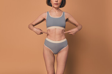 No filter photo of slender skinny elderly woman body diet effect isolated on beige color background