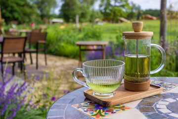 Serving tea with a teapot in a rustic bistro with a vium in flover's garden