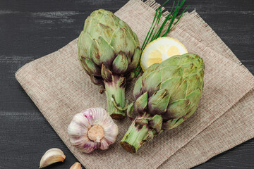 Fresh green artichokes cooking on wooden background. Traditional seasonal ingredients