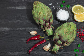 Fresh green artichokes cooking on wooden background. Traditional seasonal ingredients