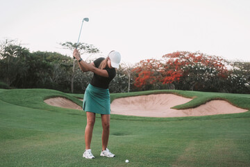 Banner with a young woman playing golf at a country club. She swings the club to hit the ball and goal the hole. Focus and concentration while playing. Professional.
