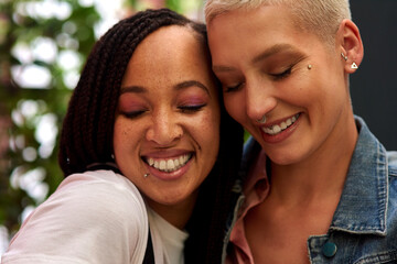 Happy woman, lesbian and interracial couple with hug, love or care for embrace, LGBTQ or friendship in nature. Female person, friends or homosexual with smile for outdoor romance or relationship