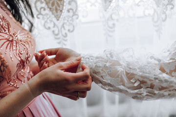 A woman is getting ready for a wedding and is adjusting her dress. The dress is white and has a...