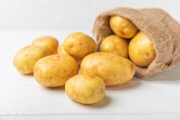 Young potatoes. Fresh potatoes on a wooden background. potato in burlap sack. Harvesting collection. organic, freshly dug potatoes. Agricultural background. Vegan. Vegetables.Place for text.Copy space
