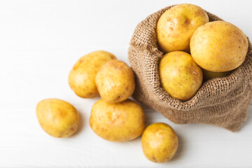 Young potatoes. Fresh potatoes on a wooden background. potato in burlap sack. Harvesting collection. organic, freshly dug potatoes. Agricultural background. Vegan. Vegetables.Place for text.Copy space