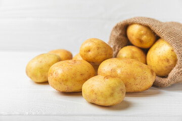 Young potatoes. Fresh potatoes on a wooden background. potato in burlap sack. Harvesting collection. organic, freshly dug potatoes. Agricultural background. Vegan. Vegetables.Place for text.Copy space