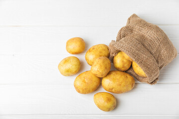 Young potatoes. Fresh potatoes on a wooden background. potato in burlap sack. Harvesting...