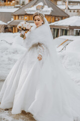 A bride in a white dress is holding a bouquet of flowers and wearing a fur stole. The scene is set in a snowy environment, with a house in the background