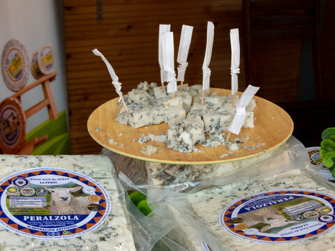 OVIEDO, SPAIN - MAY 10, 2024: Peralzola blue mould sheep cheese degustation with wooden sticks on the Fair of Ascension Day in Oviedo,Asturias,Spain. La Peral cheese dairy.