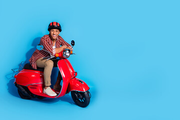 Full length photo of cheerful guy wear stylish t-shirt helmet ride on moped near promo empty space...