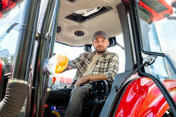 Naklejka premium Photo of male agricultural farmer in a tractor cabin.