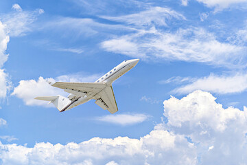 Private business plane flying under a blue sky with white clouds