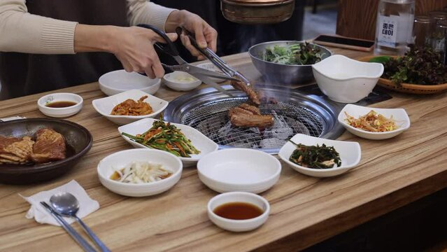 Cutting Fresh Meat on Smoking Barbecue Grill in Korean Restaurant