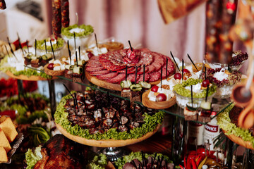 A table full of food with a variety of meats and vegetables. The table is set up for a party or gathering