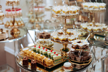 A table full of desserts with a variety of flavors and colors. Scene is celebratory and indulgent, as it is a dessert buffet for a special occasion