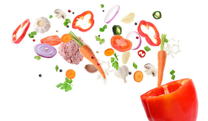 Stuffed pepper recipe. Fresh ingredients falling into bell pepper on white background