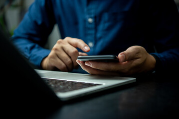 A man is using a cell phone while sitting at a desk