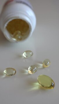 Fish oil omega 3 supplements spilling out of a packer bottle on a white background